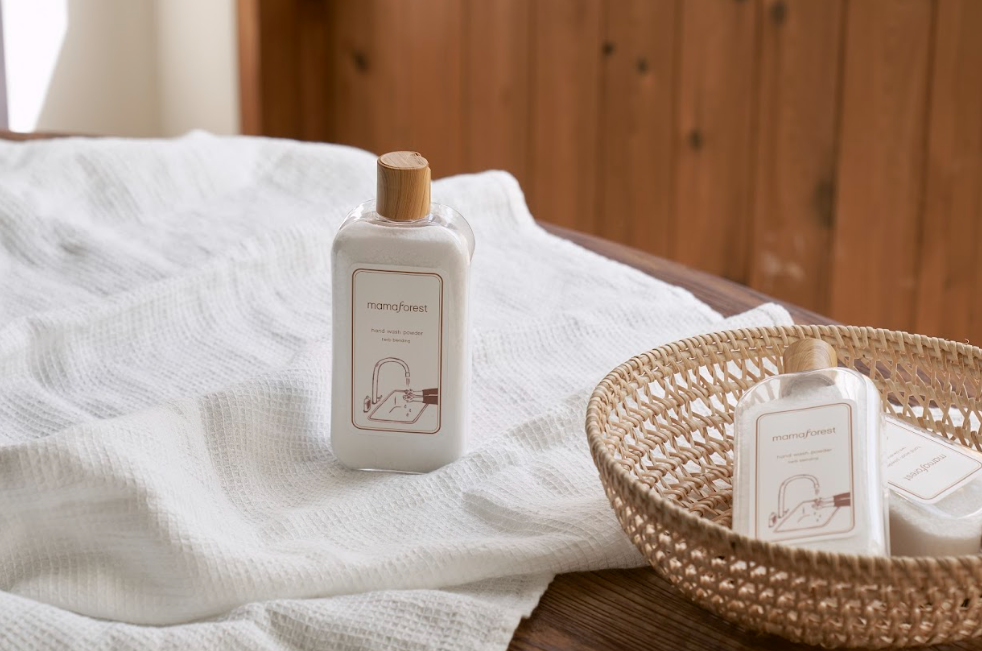 Two bottles of hand wash powder with one on a towel and on in a basket